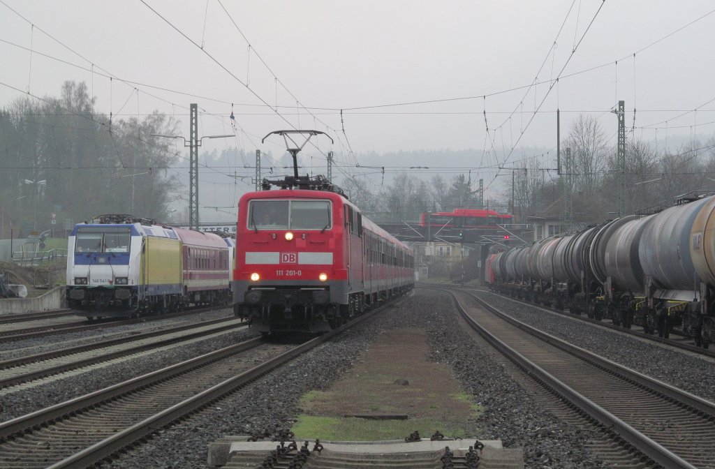 111 201-0 erreicht am 13. April 2012 mit dem morgendlichen Pendlerzug aus Saalfeld den Kronacher Bahnhof auf Gleis 3. Derweil wartet auf Gleis 1 eine 152 mit einem Kesselzug auf die Streckenfreigabe in Richtung Saalfeld. Auf Gleis 2 ist das Signal gerade fr einen weiteren Gterzug auf grn gesprungen und auf Gleis 5 pausieren zwei 146er samt Euro-Express-Wagen.