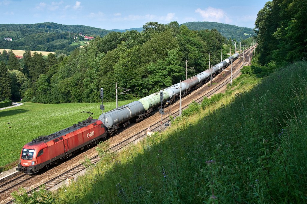 1116 067 ist mit einem Kesselwagenganzug Richtung Westen unterwegs. Die Aufnahme entstand am 10.07.2013 kurz vor Unter Oberndorf, Richtung Westen.