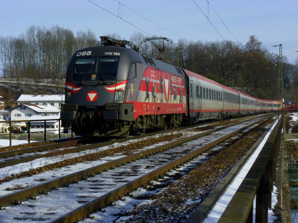 1116 138 mit Werbung fr Heeres-Sport rollt mit einem OIC in Richtung Kufstein auf der Eisenbahnbrcke ber den Inn in Rosenheim. (27.01.13)