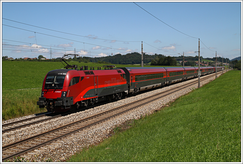 1116.224 und Zwischen-Tfz 1116.233 ziehen den RJ 564 in Krze durch die kleine Ortschaft Weng. 02.08.2011