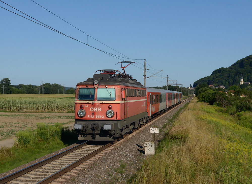 1142 564  Flurli  war gestern den 22.07. mit der Schnellbahngarnitur S5 (Zug 4148) von Spielfeld-Stra nach Graz Hauptbahnhof unterwegs, und wurde von 
mir in Neudorf ob Wildon fotografiert. Rechts ist Wildons  Barockkirche St.Magdalena, welche vom Grazer Baumeister Franz Isidor Carlone errichte wurde zu sehen. 