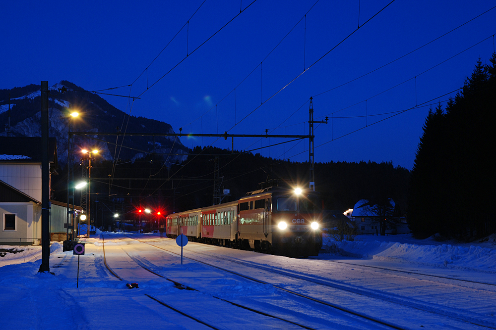 1142 671 mit REX 3431 in der Abenddmmerung des 09.02.2011 im Bahnhof Tauplitz. Dieser verfgt als einer der letzten der Salzkammergutstrecke noch ber die originalen Fahrleitungsanlagen aus der Zeit der Elektrifizierung.