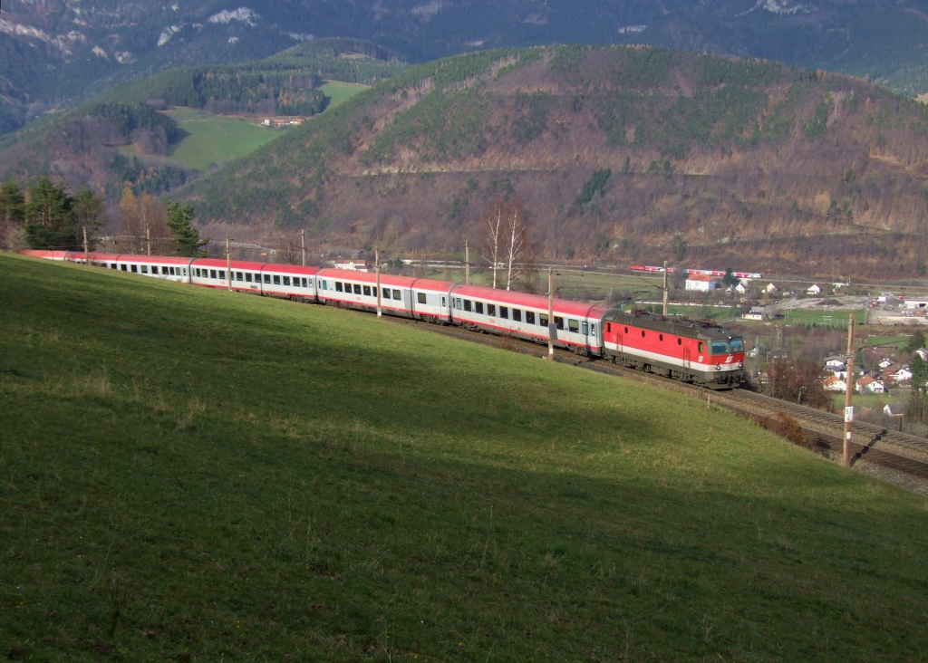 1144 276 [inzwischen ohne Pflatsch] am OIC 257 Wien Meidling–Maribor auf der Apfelwiese in Eichgraben (Semmering). [25.11.10]
Wenn ein Zug durch’s Tal rauscht und oben zehn Minuten spter vorbeifhrt, kommt herrliches, fr einen Flachlndler ungewohntes Gebirgsbahn-Feeling auf! Fr die Dosto-Garnitur ist allerdings wegen des zu breiten Profils in Payerbach-Reichenau (imaginr links auerhalb des Bildes) Endstation.
