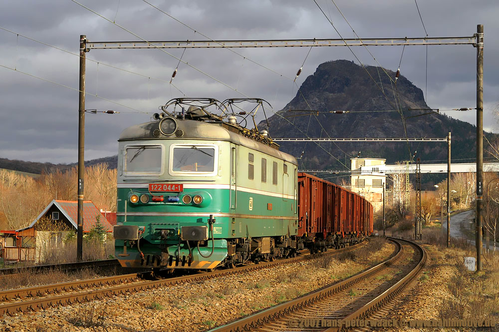 122 044 fhrt durch den Bahnhof elenice in Richtung Most. Im Hintergrund der Vulkanberg Bořeň, der von allen Seiten zu sehen ist und zweifellos ein Wahrzeichen Bilinas darstellt und sich als Hintergund fr die Eisenbahn hervorragend macht. Die Hhe betrgt 539 Metern ber NN. Aufnahme vom 20.01.07.