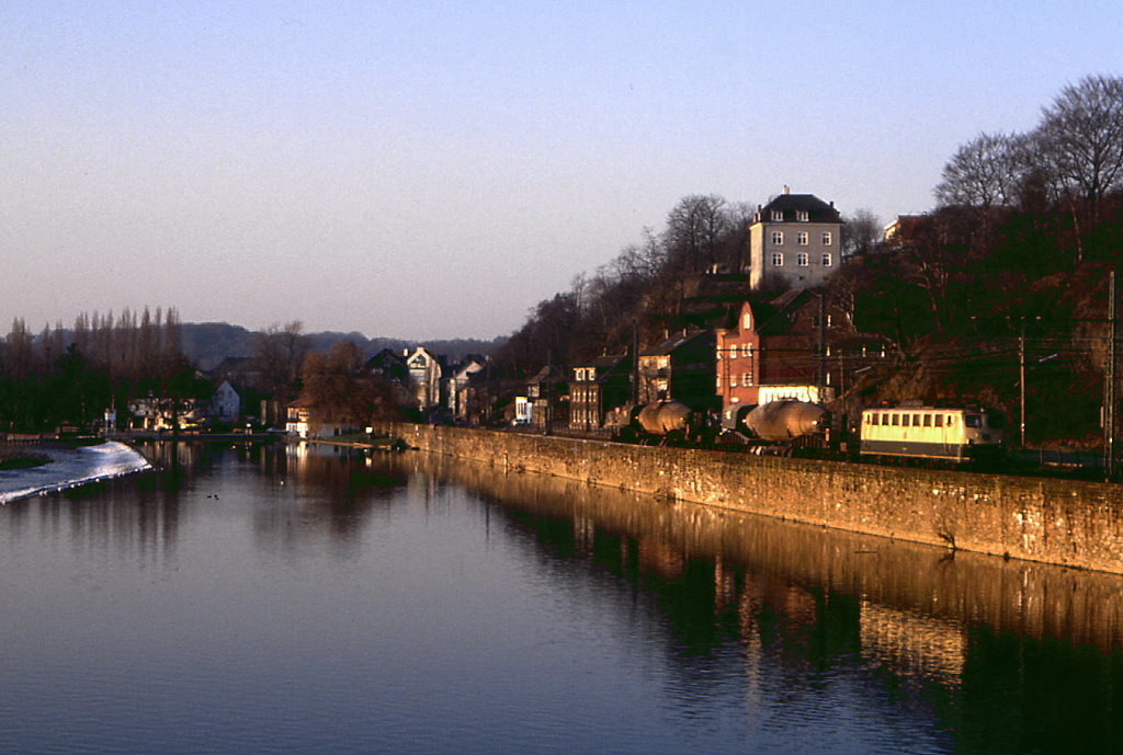 140 281 passiert mit einem Zug zur Hattinger Henrichshtte bei Bochum Dahlhausen die aufgestaute Ruhr, 10.02.1989.
