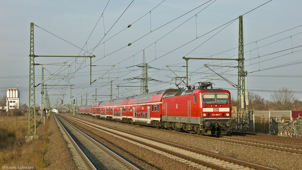 143 816-7 ist mit ihrem RE aus Halle (Saale) an der S-Bahn-Station Halle Messe unterwegs nach Leipzig Hbf. Im Hintergrund ist noch der Gegenzug zu erkennen. (26.11.2011)