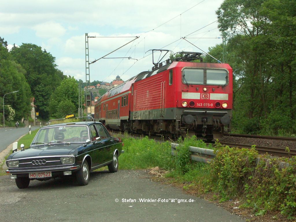 143075 mit einem Dosto-Zug verlsst Kronach am 13.Juni 2010 und trifft einen alten Audi, der wohl anl. eines Auditreffens dort zugegen war.