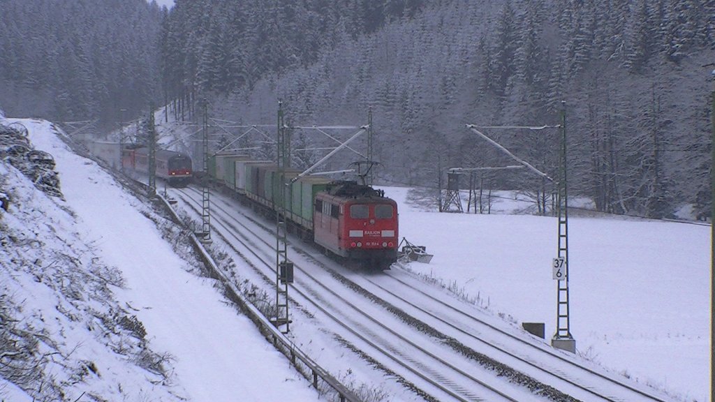 151 153-4 schiebt am 28.01.2012 den Hangartner KLV, gezogen von BR 185, ber die Frankenwaldrampe zwischen Frtschendorf und Steinbach am Wald. Desweiteren ist eine Regionalbahn / RB aus Saalfeld (Saale), bestehend aus einem Karlsruher Steuerwagen, einem Bnrz und einer BR 111 am Zugschluss in Gegenrichtung unterwegs. 