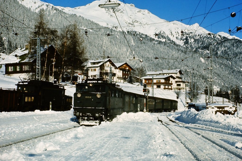 1670.105 erreicht Mitte der 1970er Jahre an einem Tag im Dezember mit dem Personenzug aus Landeck St. Anton am Arlberg. Eine 1020 wartet mit Gterzug auf die Ausfahrt Richtung Innsbruck.