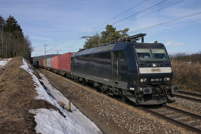 185-551 der MRCE in der warmen Mittagssonne mit einem Containerzug.(KBS 880,bei Parsberg,27.02.2010)