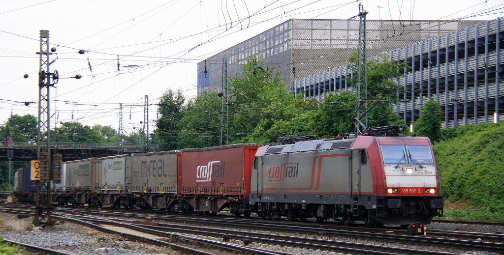 185 597-2 von Crossrail kommt aus Richtung K�ln,Aachen-Hbf mit einem langen Ewals-Cargo-Care-Containerzug aus aus Novara(I) nach Genk-Zuid-Haven(B) und f�hrt in Aachen-West ein in der Abendsonne und Wolken am Abend vom 26.6.2013.