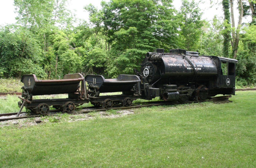 18.6.2012 Lok mit Loren im Museum of Industrial History, Kent, CT. Ob eine Feldbahn hier langlief ist mir unbekannt. In unmitterlbarer Nhe verluft die Linie der Housatonic Railroad. Aufschrift: American Steel & Wire Company.