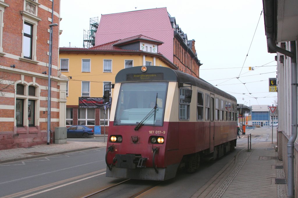 187 017 der HSB fhrt am Vormittag des 06.04.2012, von der Straenbahnhaltestelle auf dem Nordhausener Bahnhofsvorplatz (im Hintergrund zu sehen) kommend, ber die Oscar-Cohn-Strae und wird gleich das Gleisnetz der Harzer Schmalspurbahnen erreichen.
