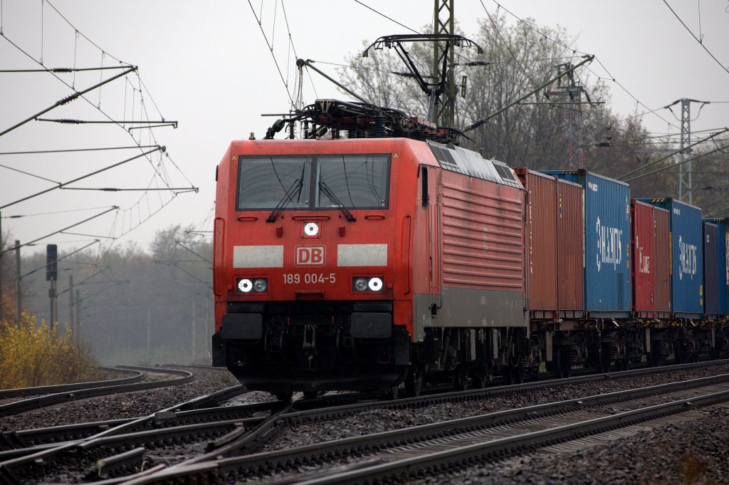 189 004 - 5 auf der Kreuzung in Radebeul Naundorf, um 10:58 Uhr am 11.11.2012 einen langen Containerzug beschleuinigend, im tr�ben Novemberregen.