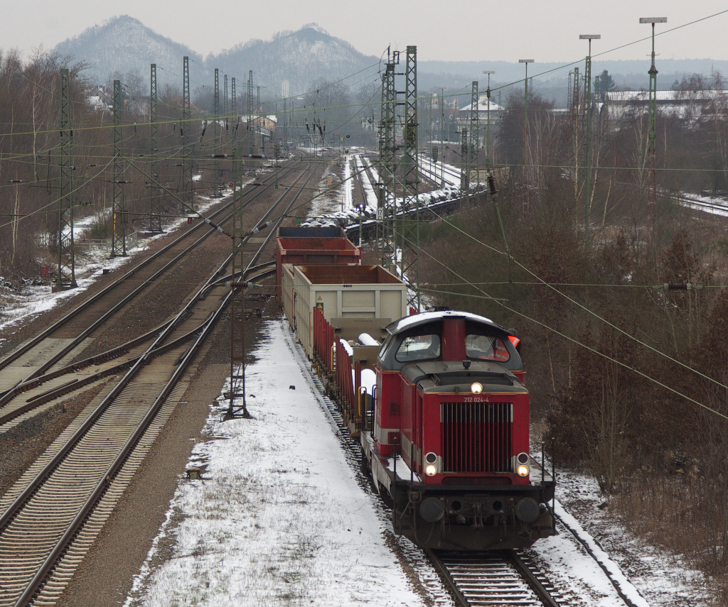 212 024-4 wurde als V 100 2024 im Jahr 1963 in Dienst gestellt.

Seit Dezember 2012 gehrt sie zur Firma  Heinrichsmeyer Eisenbahndienstleistungen  in Trier und damit zum Verbund der HWB - Hochwaldbahn.

Am 01.06.2011 hat die HWB fr zunchst drei Jahre das Rangiergeschft im Stahlwerk Bous im Saarland (bei Saarlouis) bernommen.

212 024 hat ihren Zug aus dem Stahlwerk (rechts) ausgezogen und schiebt ihn nun auf ein Abstellgleis.
Man sieht dass die Gleisanlagen zur Zeit der Mannesmann Rhrenwerke weitlufiger waren. 

12.02.2013
