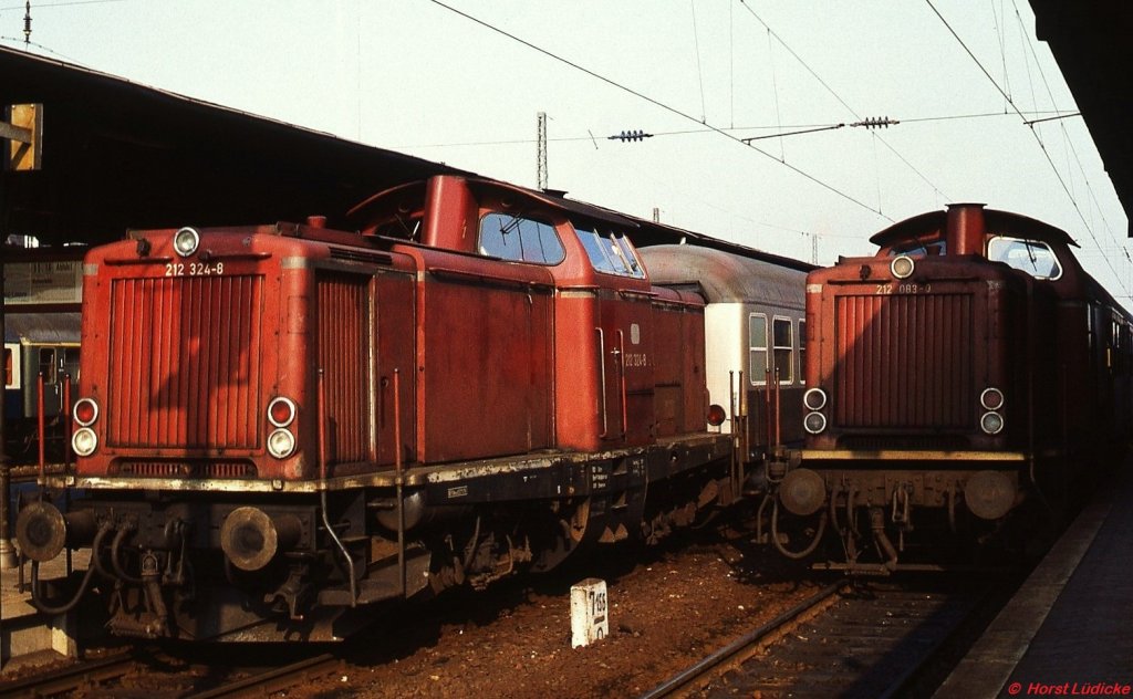 212 083-0 und 212 324-8 begegnen sich im Sommer 1978 im Bahnhof Solingen-Ohligs (heute Solingen Hbf.). Mit der Erffnung der S 7 im Jahr 1980 entfielen die meisten durchgehenden Verbindungen nach Dsseldorf und die weiter in Richtung Solingen Stadtmitte bzw. Remscheid reisenden Fahrgste mssen hier umsteigen. Am Kilometerstein ist erkennbar, dass die Kilometrierung in Ohligs neu beginnt.