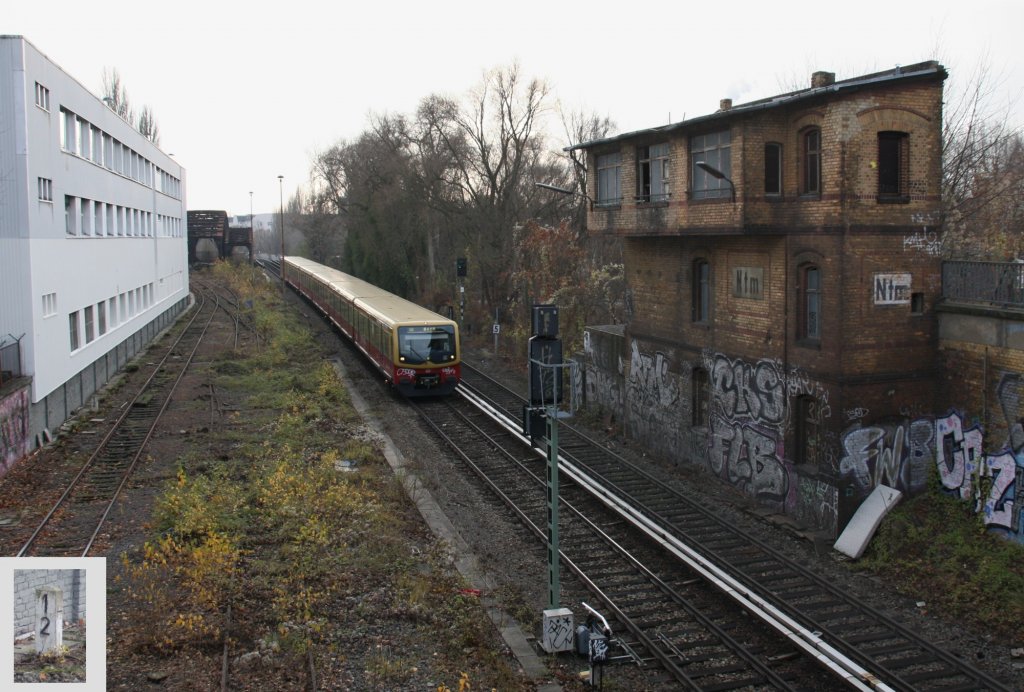 2.12.2012 S2 nach Buch passiert zwischen Berlin-Nordbahnhof und Humboldthain Stellwerk Ntm. Durch den Rckschnitt von Pflanzen werden die Gleise der alten Berlin-Stettiner Bahn sichtbar. Kilometerstein 1.2 ist vermutlich der erste der noch verbliebenen.