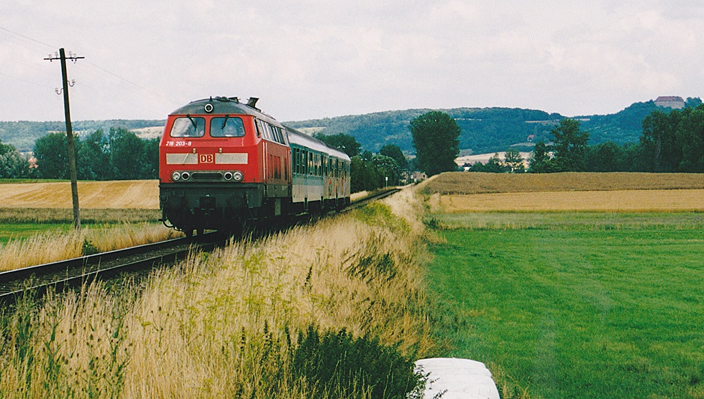 218 203 auf dem Weg nach Steinach. Am Bahnbergang hinter dem Zug lag frher der Haltepunkt Oberndorf, und von der Anhhe am rechten Bildrand grt die Burg Hoheneck.