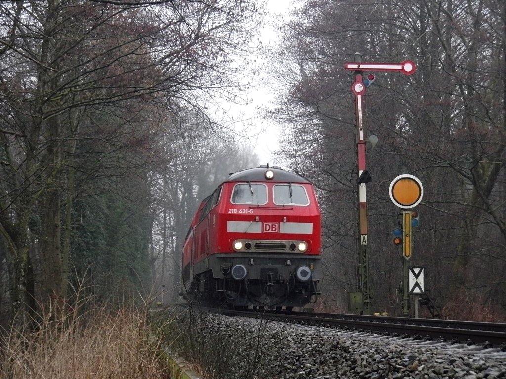 218 431-5 mit IRE 4230 von Lindau nach Stuttgart passiert am 20.02.2011 bei grauem Himmel und Regen die Einfahrsignale von Lindau-Enzisweiler.