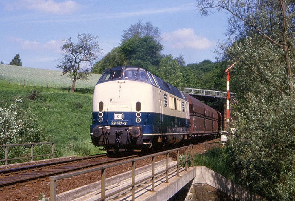 221 147 bei Heiligenhaus Hofermühle, 25.05.1986. Damals war Hofermühle noch ein Bahnhof und zumindest werktags einige Stunen lang besetzt. So jedoch nicht zum Aufnahmezeitpunkt, was das durchgeschaltete Signal belegt.