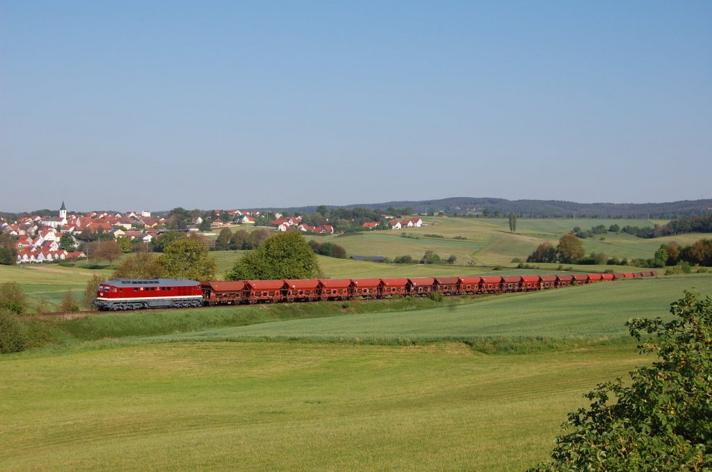 232 088 am 19.05.2011 mit einem langen Schotterzug vor der Kulisse des Ortes Gebenbach. (Strecke Amberg-Schnaittenbach)