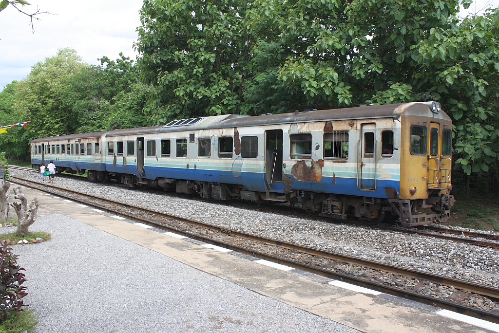 กซข.1024 (กซข. = BPD/Bogie Power Diesel Railcar With Driving Cab, Hitachi/Nippon Sharyo, Bauj. 1971) mit dem พซข.16 (พซข. = BTD/Bogie Trailer Diesel Railcar With Driving Cab, Hitachi, Bauj. 1967) wartet am 18.Juni 2011 als ORD 434 nach Kaeng Khoi Jn. im Bf. Khok Khli auf die Kreuzung mit einem Schotterzug.

