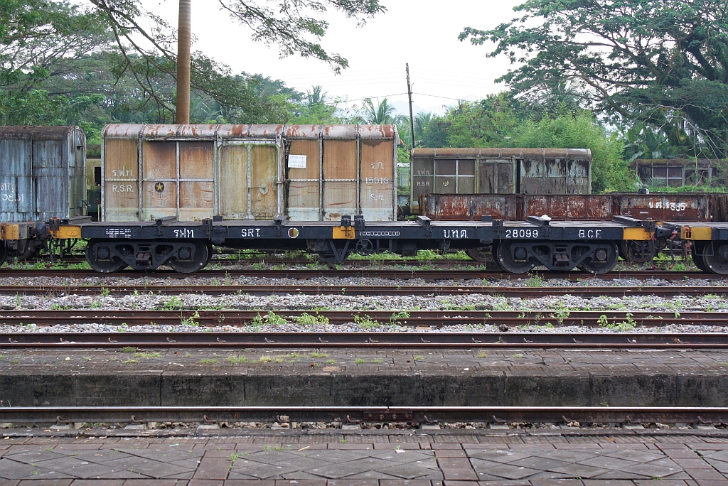 บ.ท.ต. 28099 (บทต = B.C.F./Bogie Container Flat Wagon) am 07.Jänner 2013 im Bf. Thung Song Junction. Der Wagen wurde 1956 von Fuji Car Mrg.Co.Ltd. in Osaka/Japan als B.F.W. 335(Bogie Flat Wagon) gebaut und später von den SRT zum B.C.F.(Bogie Container Flat Wagon) umgebaut. 

