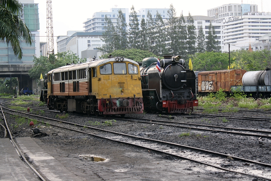 4041, daneben die betriebsfähig abgestellte 953, wartet am 13.März 2011 im Depot Thon Buri auf ihren Einsatz vor dem ORD 257 nach Nam Tok. Das grüne Gebäude links im Bild ist der Erweiterungsbau des Sirirat Hospital, desenwegen die ursprüngliche (19.Juni 1903 eröffnet) Thon Buri Station am 05. Oktober 2003 geschlossen wurde und die damalige Bangkok Noi Station in Thon Buri umbenannt wurde.