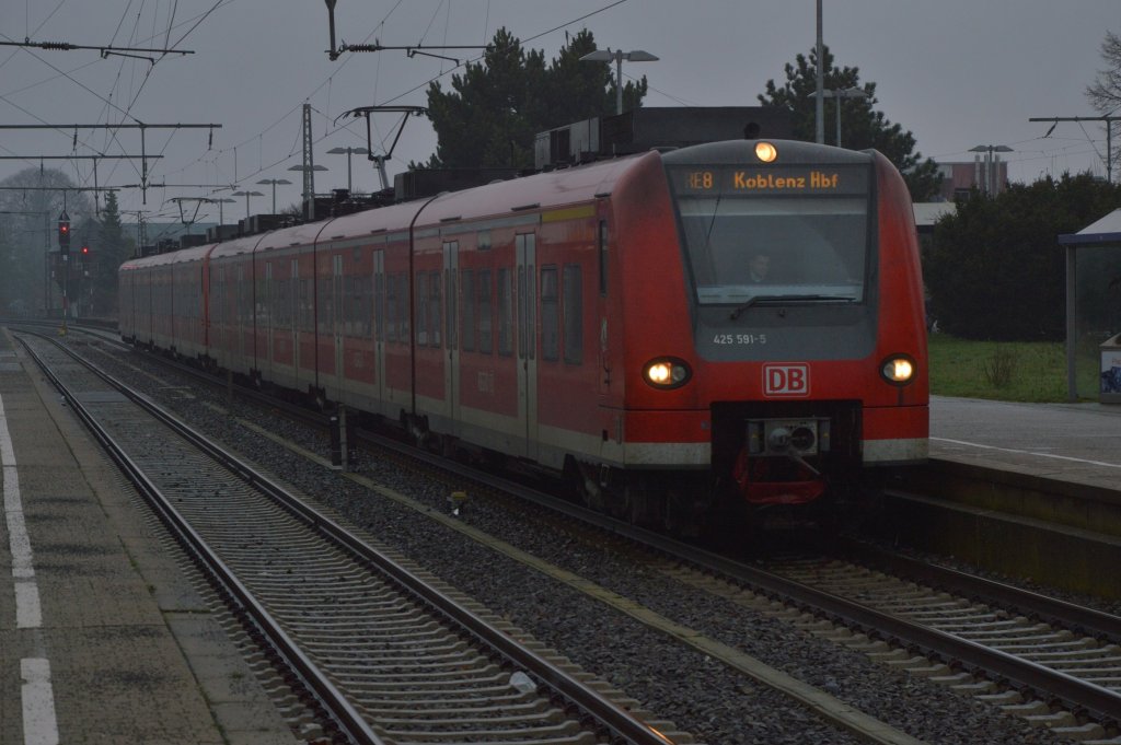 425 591-5 ist der Steuerkopf eines RE 8 Zuges nach Koblenz, der gerade im Rheydter Hbf steht und das bei typischem rheinischem Landregen. Nach wenigen Minuten nimmt er wieder Fahrt auf, um in die Kbs 465 ein zu  biegen in Richtung Rhein. 4.1.2012