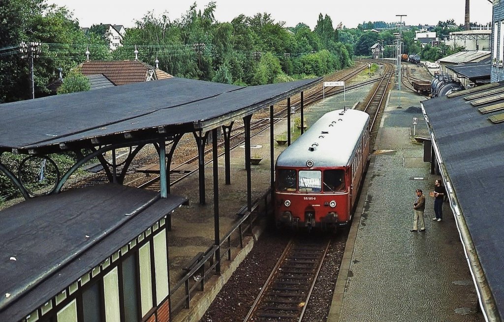 515 565-0 fährt im April 1986 auf seinem Weg nach Opladen im Bahnhof Burscheid ein. Am 31.05.1991 wurde das Reststück Opladen - Hilgen der früher zweigleisigen, bis Remscheid-Lennep führenden Strecke stillgelegt. Das rechts (nicht sichtbare) Empfangsgebäude steht heute noch, während der hübsche Bahnsteig abgerissen worden ist und sich die Natur das ehemalige Bahngelände zurückerobert hat.