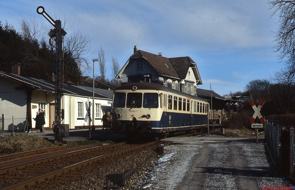 515 604-7 verlässt Mitte Februar 1988 den Bahnhof Wuppertal-Küllenhahn in Richtung Stadtmitte. Die in Wuppertal-Steinbeck von der Hauptbahn abzweigende, knapp 11 km lange Strecke überwand bis zum Endpunkt Cronenberg einen Höhenunterschied von 140 m. Sie verlief durchgehend auf Wuppertaler Stadtgebiet, meist durch dichten Wald, und bot zahlreiche Fotomotive. Heute verläuft auf der Trasse ein Radweg.