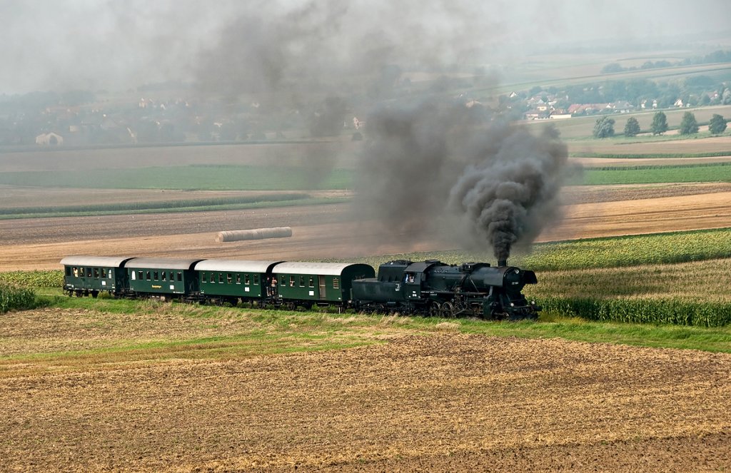 52 100 dampft mit REX 7388 der Haltestelle in Mollmannsdorf entgegen. Sptsommer im Weinviertel, am 15.08.2010.