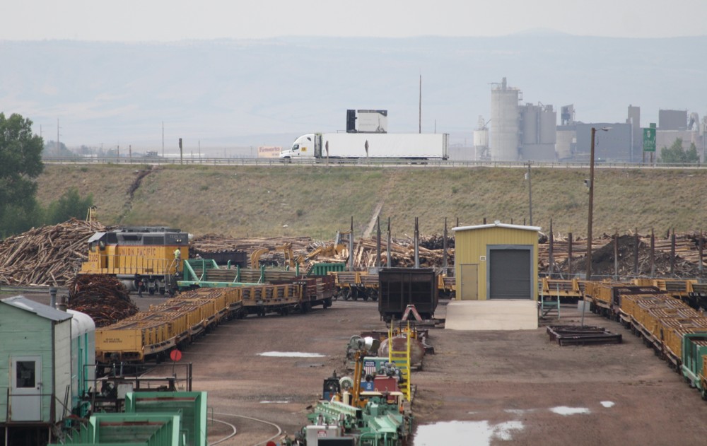 5.7.2012 Laramie, WY. Union Pacific Yard. UP 3205 (SD 40) rangiert Wagen mit geschweiten Schienen (Schienen werden hier im Bahnhof verschweit), dahinter ein Truck auf Interstate 80 sdwrts und dahinter einer Zementfabrik.