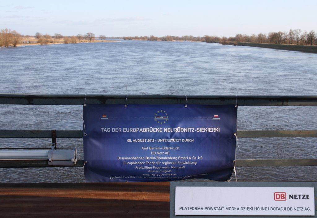 5.8.2012 Oderbrcke zwischen Wriezen und Jdickendorf. Erinnerungsplakat anllich der Europabrcke. An einem nebenstehenden Pfeiler ein DB Netze Schild in Polnisch. Irgendwas ergab sich dank grozgiger Zuwendungen. bersetzungshilfe erbeten.