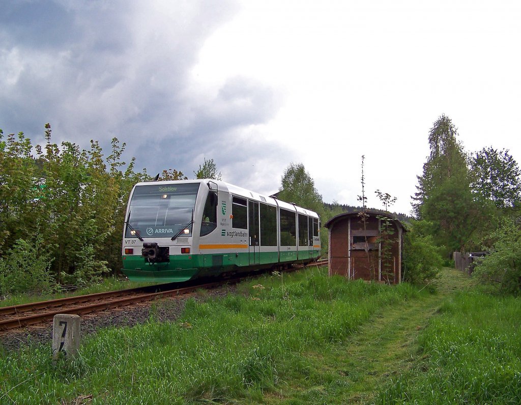 654 037 (VT37) als VBG83120 in Klingenthal, 28.5.010. An diesem Tag bestand die grenzberschreitende Strecke Klingenthal - Graslitz genau 10 Jahre. Rechts neben dem Tw der Wagenkasten stammt brigens noch von der ehemaligen Klingenthaler (berland-) Straenbahn in den heutigen Stadtteil Sachsenberg-Georgenthal. Als Treffpunkt  Graue Maus  war er bei den Klingenthalern frher sehr beliebt.