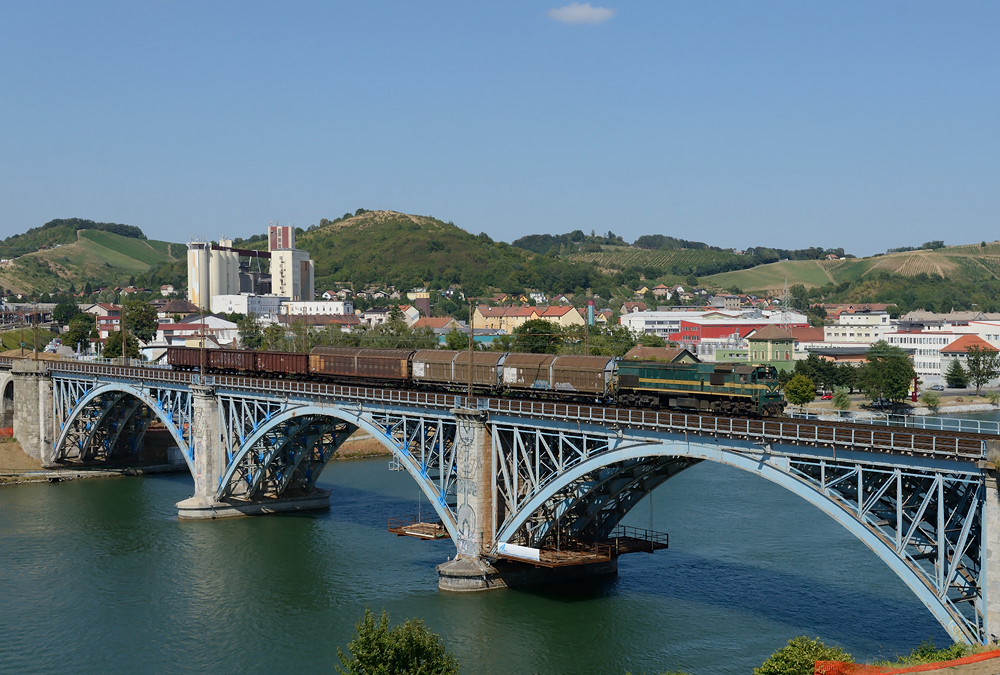 664 113 berquerte am Nachmittag des 12.08.2013 mit einem gemischten Gterzug in Fahrtrichtung Pragersko/Pragerhof die Draubrcke in Maribor/Marburg.

