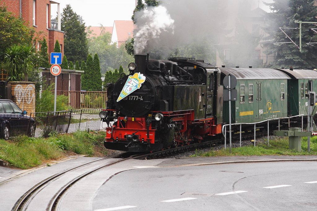 99 1777 hat am Mittag des trben 31.08.2012 mit ihrem Personenzug P 3006 nach Moritzburg soeben den Bahnhof Radebeul-Ost verlassen und berquert gleich die Schildenstrae im Radebeuler Stadtgebiet. Diese Aufnahme entstand eher zufllig: Whrend einer Regenfahrt auf der Autobahn hatte mein Heckscheibenwischer den Geist aufgegeben. Auf der Suche nach einer Werkstatt, hatte ich mich in Radebeul hoffnungslos verfahren und geriet just an diese Kreuzung. Genau in diesem Moment ging die Warnblinkanlage des Bahnberganges in Betrieb. Die Kamera schnappen und aus dem Auto raus, war eins! Manchmal hat man ja doch ein Quentchen Glck! ;-) brigens, die Werkstatt hebe ich dann auch noch gefunden!! ;-)