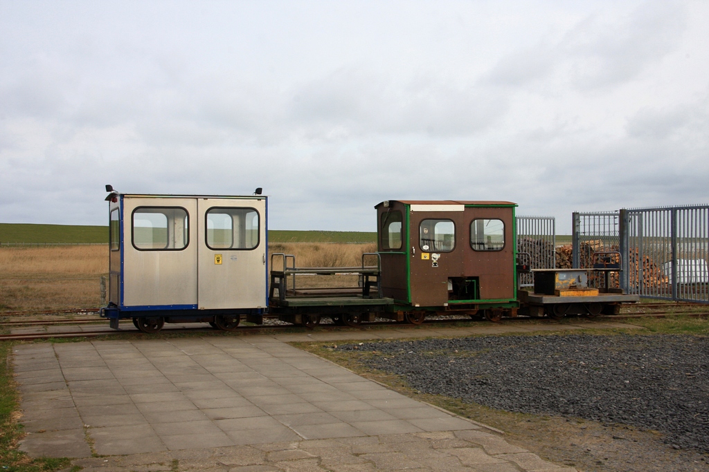 Abgestellte Loren (v.l.n.r. Lore 1, Wagen, Lore 9, Lore 4) vor dem Betriebshof des LKN-SH in Lttmoorsiel. Lore 1 wurde erst im Vorjahr umgebaut, man kann es aber auch einen Neubau unter Verwendung altbrauchbarer Teile nennen. Die eh. Lore 1 von Bild 397 364 ist nicht wiederzuerkennen. (Halligbahn Lttmoorsiel - Nordstrandischmoor, 23.04.2010)