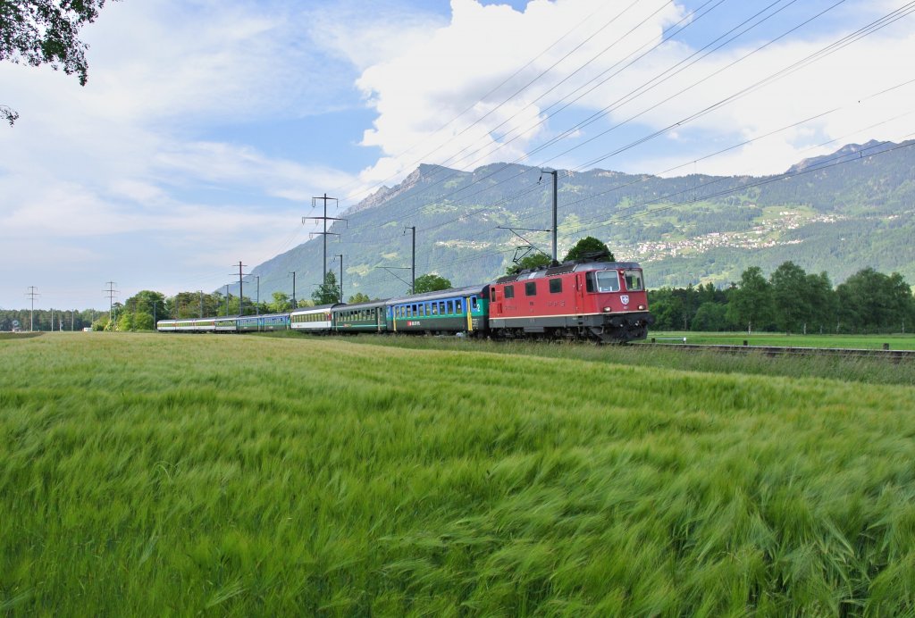 Abschied des lokbespannten Rheintal Express: RE 3827 mit der Re 4/4 II 11210 bei Weite. Planmssig verkehren die RE mit 4 Wagen, zur HVZ werden div. Zge verstrkt. Jeweils 1 Zugspaar am Morgen und eines am Abend wurde mit 5-Wagen verstrkt (im Bild ist der  Abend  Zug), 07.06.2013.

