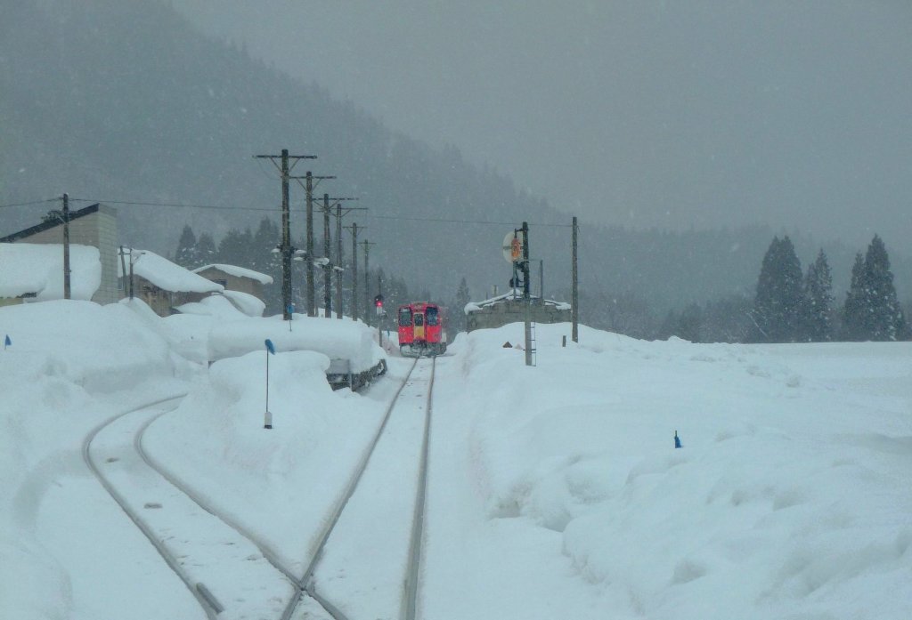 Akita Nairiku-Bahn, die 1963 erffnete Verlngerung des Nordabschnitts - der rote Triebwagen 8806. Ausfahrt aus Hitachinai und Blick auf die Haltestellenanlage. 14.Februar 2013. 