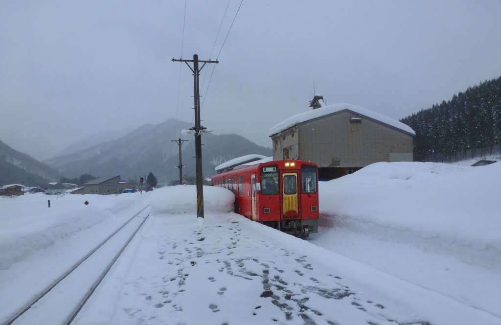 Akita Nairiku-Bahn, die 1963 erffnete Verlngerung des Nordabschnitts - der rote Triebwagen 8806: Einfahrt in Hitachinai; der Schnee auf dem Bahnsteig reicht fast bis zu seinem Dach. 14.Februar 2013. 