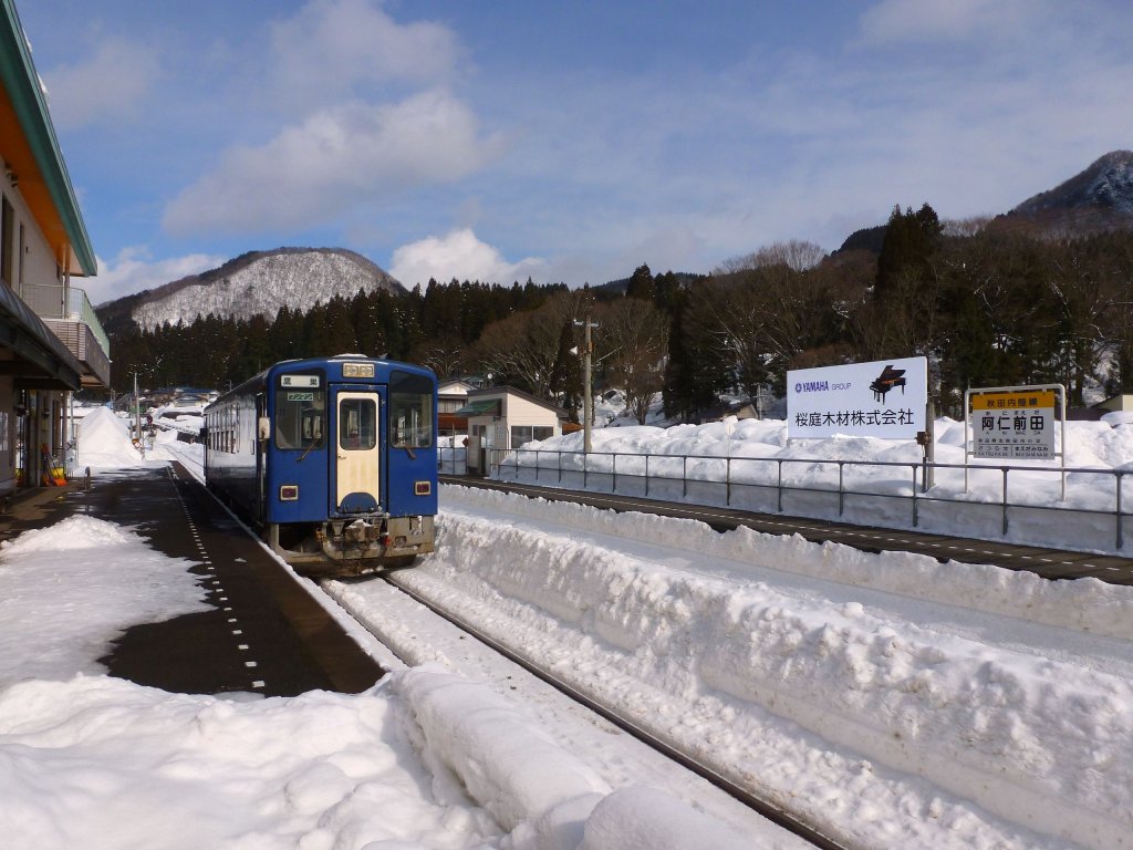 Akita Nairiku-Bahn, Nordabschnitt: Die Strecke sdwrts von Takanosu bis zu den - schon im 17.Jahrhundert weltbekannten - grossen Kupfer-, Gold- und Silberminen in Aniai wurde 1936 vollendet (33,1 km). Von dort aus erreichte die Bahn dann 1963 das Bergdorf Hitachinai 13 km weiter sdlich. 1986 wurden diese insgesamt 46,1 km Staatsbahn durch eine lokale Trgerschaft als Akita Nairiku Bahn (Nordabschnitt) bernommen. Im Bild steht auf dem Nordabschnitt Triebwagen 8805 in Ani Maeda; gut erkennbar ist auf der rechten Bildhlfte neben der Stationstafel die grosse Werbetafel fr das regionale Holz, aus dem die Yamaha-Klaviere gefertigt werden. 14.Februar 2013. 