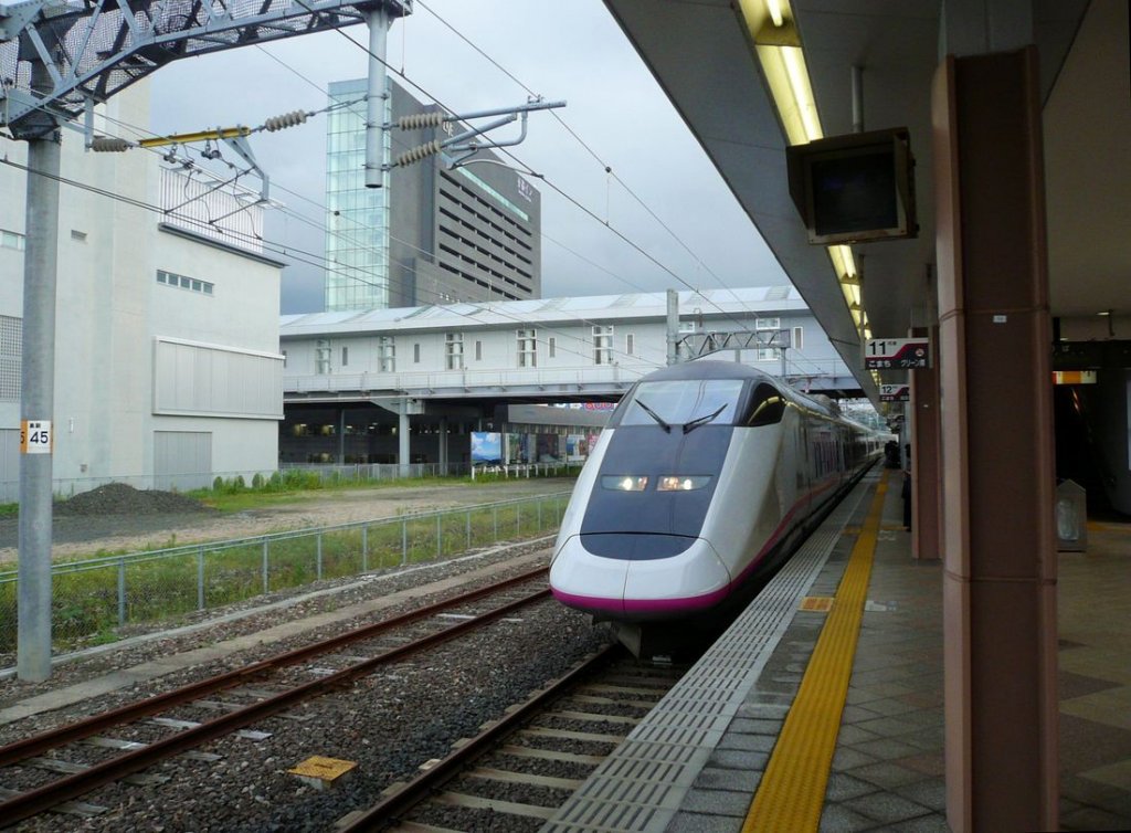 Akita Shinkansen - Serie E3: Diese Züge werden ab Tokyo bis Morioka den Shinkansen-Zügen der Tôhoku-Linie (=Nordost-Linie) vorangestellt. In Morioka kommen sie von den Shinkansen-Gleisen herunter und fahren auf der umgespurten (1067mm zu 1435mm) alten Linie quer über die Berge nach Akita am Japanischen Meer. Es gibt 26 6-Wagenzüge (sowie 3 weitere für den Yamagata Shinkansen), gebaut 1995-2005. Aufnahme des Zuges 21 (Frontwagen E311-21) bei der Einfahrt in die Endstation Akita, 10.Juli 2010. 