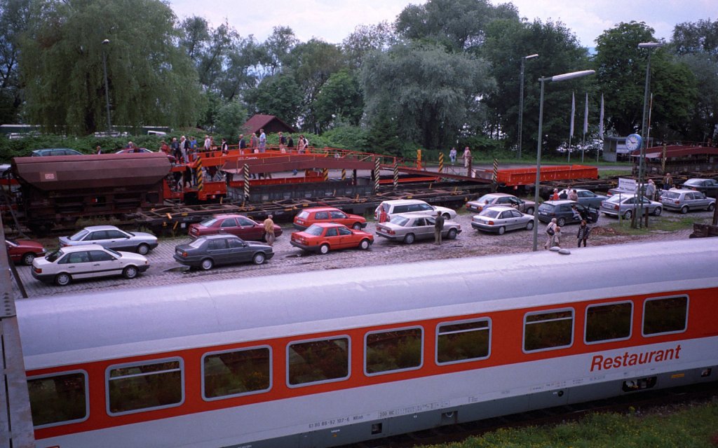 Als in Lindau-Reutin noch Autoreisez�ge ankamen/abfuhren (||). In der Bildmitte warten die Autos am 19.06.1999 auf die Auffahrt auf die Transportwagen, um anschlie�end mit dem Autoreisezug nach K�ln zu fahren. Hinter den wartenden Autos sind die gerade angekommenen Reiseg�ste zu sehen, die zu ihren auf den Transportwagen stehenden Autos gehen.