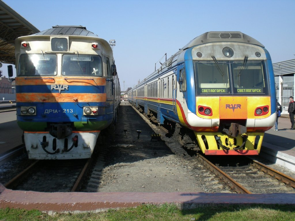 Alt und Neu bei strahlendem Sonnenschein nebeneinander im Bahnhof Gomel. Der linke Zug fuhr noch Schlobin, der rechte Zug nach Swetlogorsk. 09.04.2010 um 12:17 Uhr. 