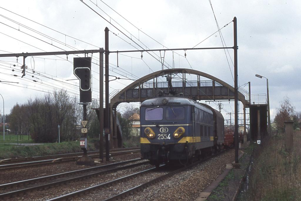 Altbau E - Lok SNCB 2554 unterquert mit einem gemischten 
Gterzug am 28.03.1997 um 11.45 Uhr die Fugngerbrcke bei Lint 
in Richtung Brssel. 