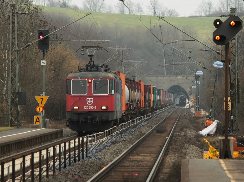 Am 03.03.2012 kommt auf der KBS 480 bei Eilendorf aus Richtung Kln 421 390-6 mit einem Containerzug am Haken durch die Baustelle zwischen Stolberg und Aachen Rothe Erde. Im Tunnel steht 212 325-5 der EfW-Verkehrsgesellschaft mit einem Flachwagenzug mit Betonschwellen, die von einem Bagger abgeladen werden.