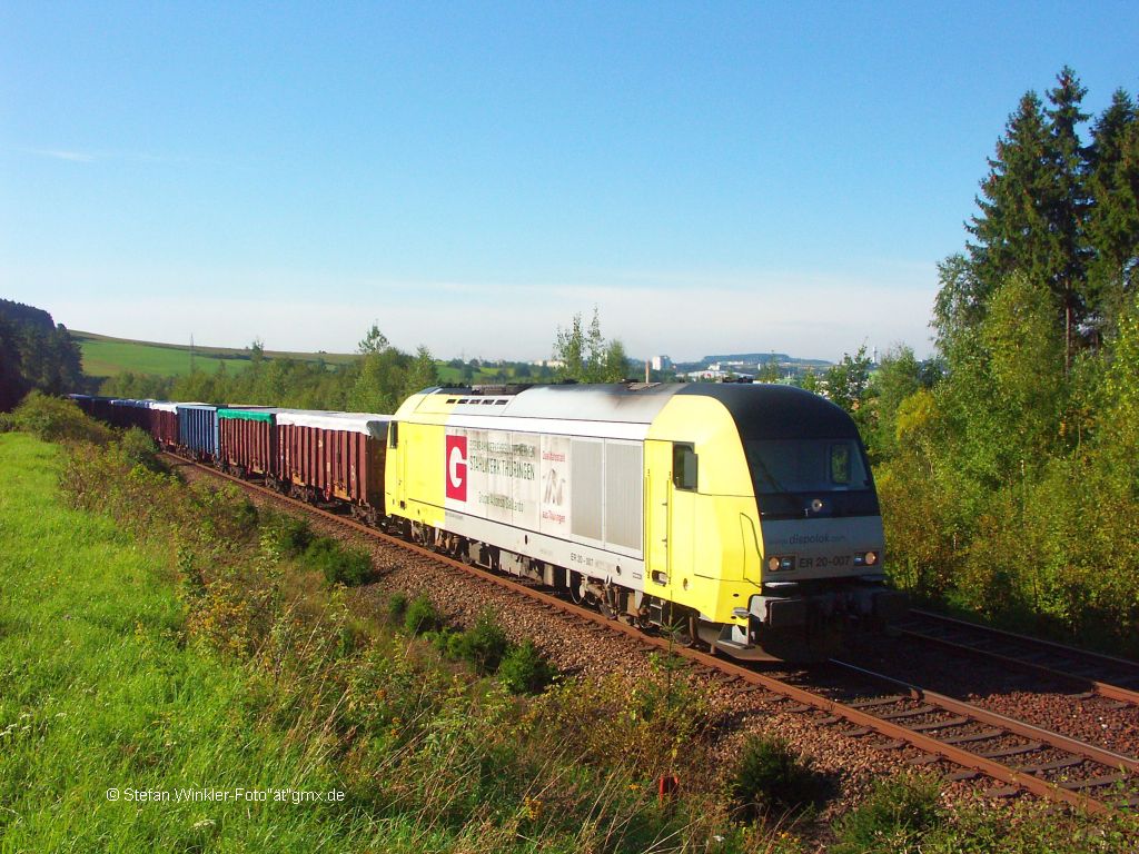 Am 07.09.2010 hatte ich auswrts was zu erledigen, sonst sitze ich um die Zeit im Bro. Die Sonne sprengte mich an die Strecke zwischen Hof und Feilitzsch. Was kam war der bekannte Schrottzug mit dem ER 20 des Eisenwerks Thringen, vormals Maxhtte Oberwellenborn..... Rechts ber der Lokomotive die Huser von Hof.