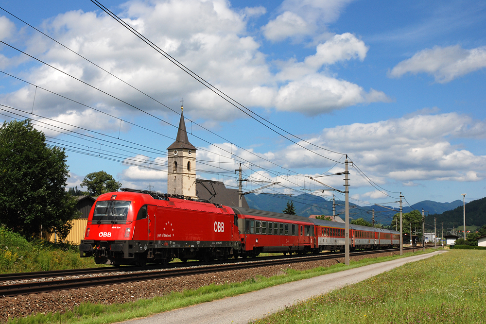 Am 21.07.2008 hatte 1216 234 den EC 100  Joe Plečnik  am Haken und wurde vor der Pfarrkirche von Kammern im Liesingtal fotografiert.