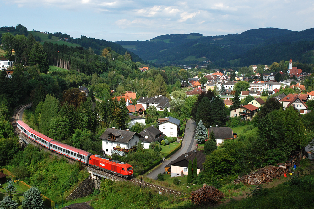 Am 21.08.2012 hat 2016 043 mit dem aus drei Fernverkehrswagen gebildeten REX 2789 nach Friedberg gerade den Bahnhof der Marktgemeinde Aspang verlassen und nimmt die ersten Meter der Steigung ber den Wechsel in Angriff. Wie vielleicht erkennbar ist, wurde bei diesem Foto das Glck bezglich Sonne und Wolken gehrig strapaziert.